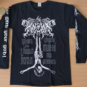 May include: Black long-sleeve shirt with a white graphic design featuring a stylized tree with a hanging figure and text in Cyrillic script that reads "здохнуть разом з вашим богом цькаючи тайний мій розігніть".