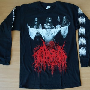May include: Black long-sleeve shirt with a band logo printed on the front. The logo is red and white and features a band name and a graphic of a band member with arms outstretched. The sleeves have a white graphic print.