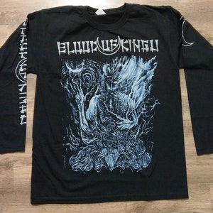 May include: Black long-sleeve t-shirt with a white graphic print of a creature with a crescent moon and the text "BLOOD OF KINGU".