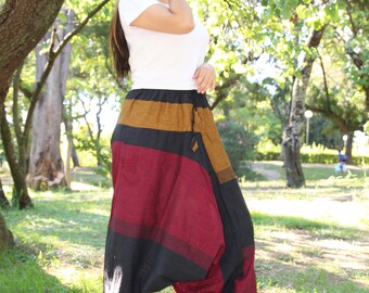 May include: A woman wearing a white t-shirt and black, brown, and red striped pants. The pants have a loose, flowing fit and are gathered at the ankles.