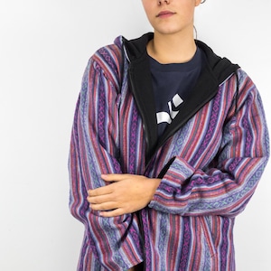 Peut inclure: Une veste à capuche rayée de violet, rose et bleu avec une fermeture éclair noire et une capuche noire.