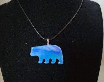 May include: A blue and white glass bear pendant on a black cord necklace.