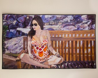 May include: A woman wearing sunglasses and a colourful patterned dress sits on a wooden bench. The bench is in front of a background of rocks and foliage.