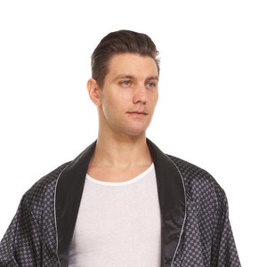 May include: A black satin robe with a white geometric pattern and a black satin trim. The robe has a shawl collar and a tie belt.