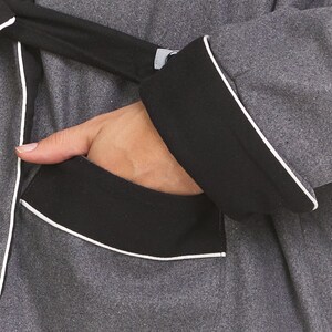 May include: A gray robe with black trim and a white piping detail. The robe has a pocket on the left side.