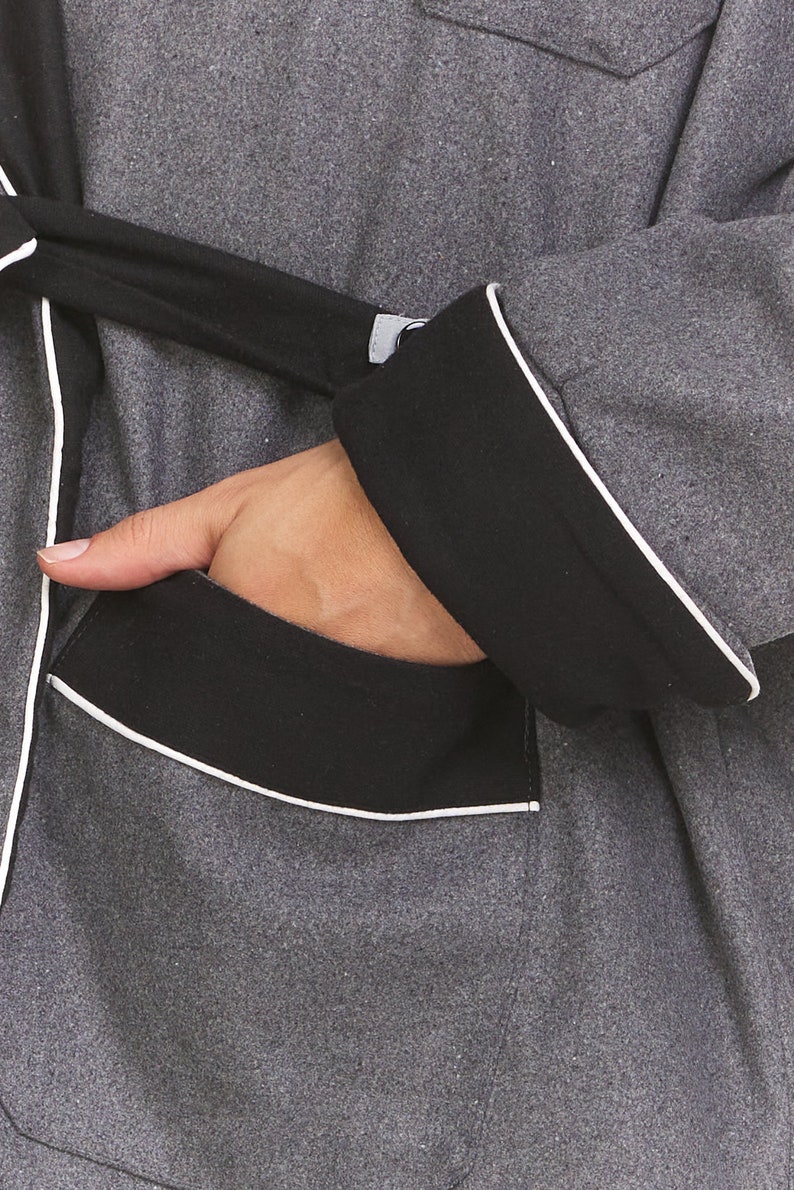 May include: A gray robe with black trim and a white piping detail. The robe has a pocket on the left side.