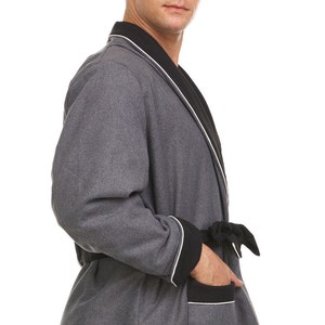 May include: A gray robe with black and white trim. The robe has a shawl collar, a tie belt, and a patch pocket on the left side.