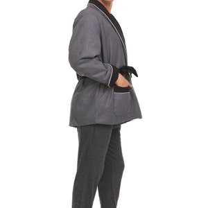 May include: A gray robe with black trim and a white piping detail. The robe has a sash tie and a patch pocket on the left side.