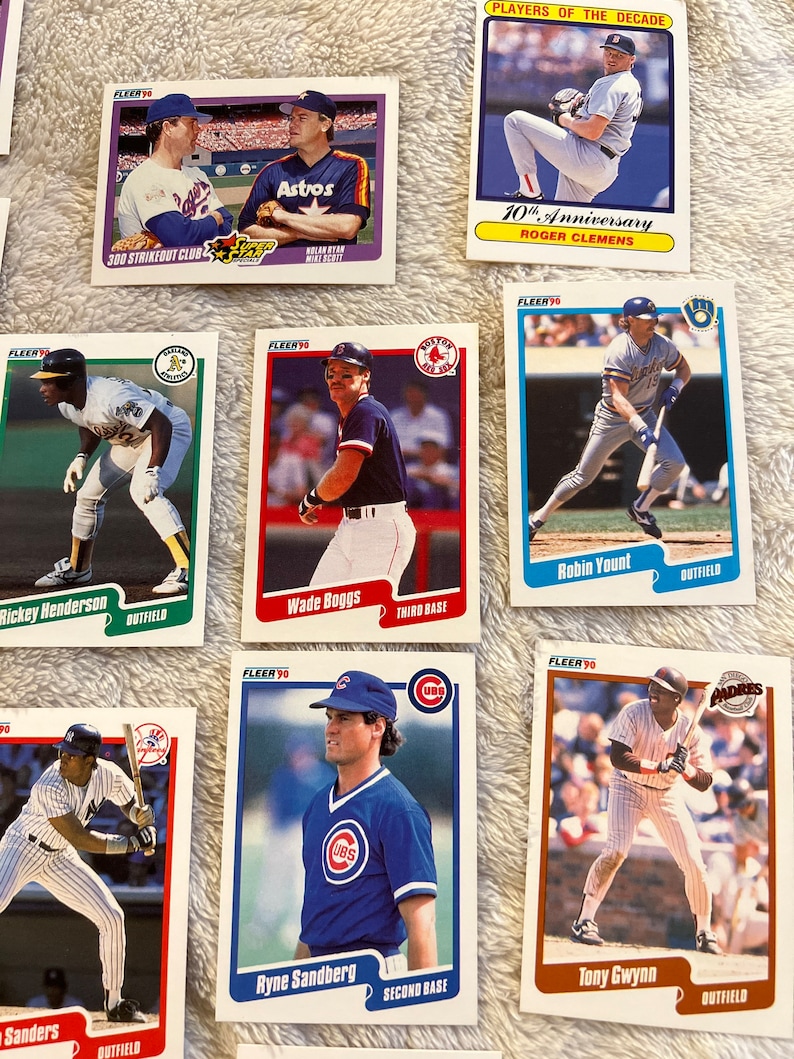 K&ouml;nnte beinhalten: Eine Sammlung von Baseball-Sammelkarten mit Spielern aus den 1990er Jahren. Die Karten stammen aus der Fleer 90-Serie und zeigen Spieler wie Roger Clemens, Wade Boggs, Robin Yount, Tony Gwynn und Ryne Sandberg.