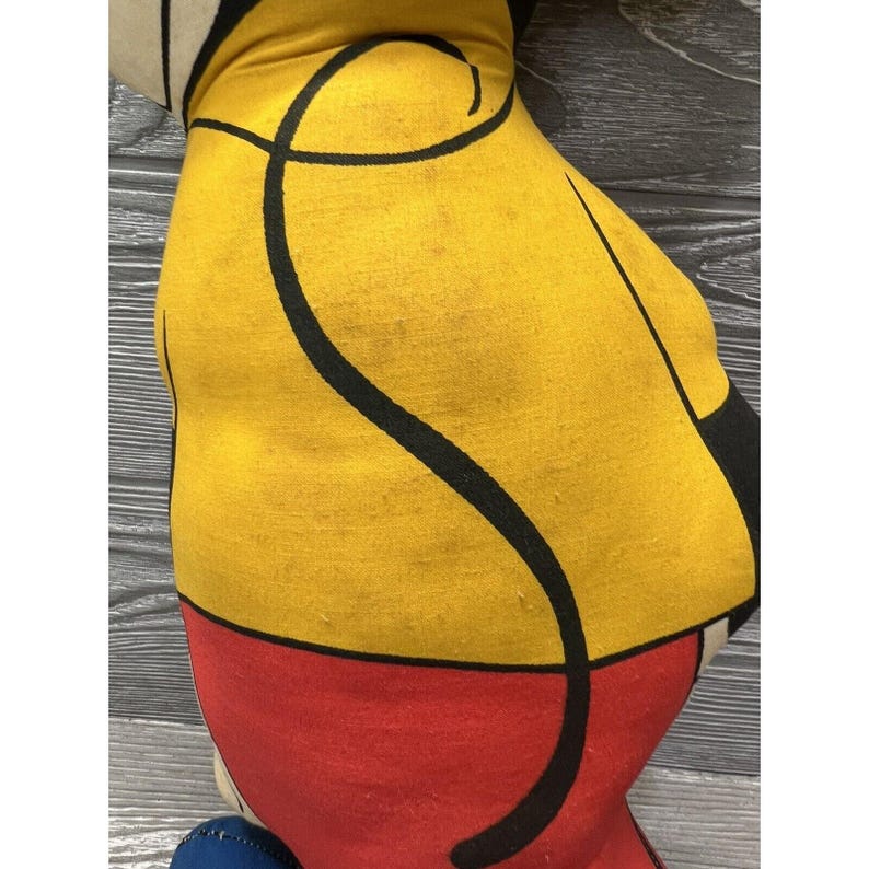 May include: A yellow, red, and black fabric pillow with a black swirl design. The pillow is made of a soft, plush fabric and is perfect for adding a touch of color and whimsy to any room.