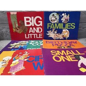 May include: A collection of seven children's books with colorful covers featuring illustrations and titles including Big and Little, Families, Birthday Pizza, and Small One. The books are arranged in a stack with various graphic designs.