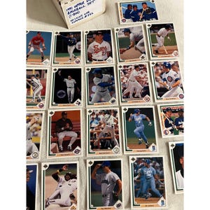 May include: A collection of 1991 Upper Deck baseball cards featuring various players. The cards are in good condition and have a white background with a green border. The text on the cards includes the player's name, team, and number. The cards are arranged in rows and columns.