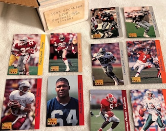 May include: A collection of 1993 Pro-Line Live Football trading cards featuring various NFL players, including Jerry Rice, Emmitt Smith, and John Elway. The cards are in a box with the text "1993 Pro-Line Live Football Set (1-285)".