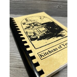 Puede incluir: Un libro de cocina de estilo vintage con una ilustraci&oacute;n en blanco y negro de una cocina en la portada. El t&iacute;tulo del libro es "Kitchens of Yesterday".