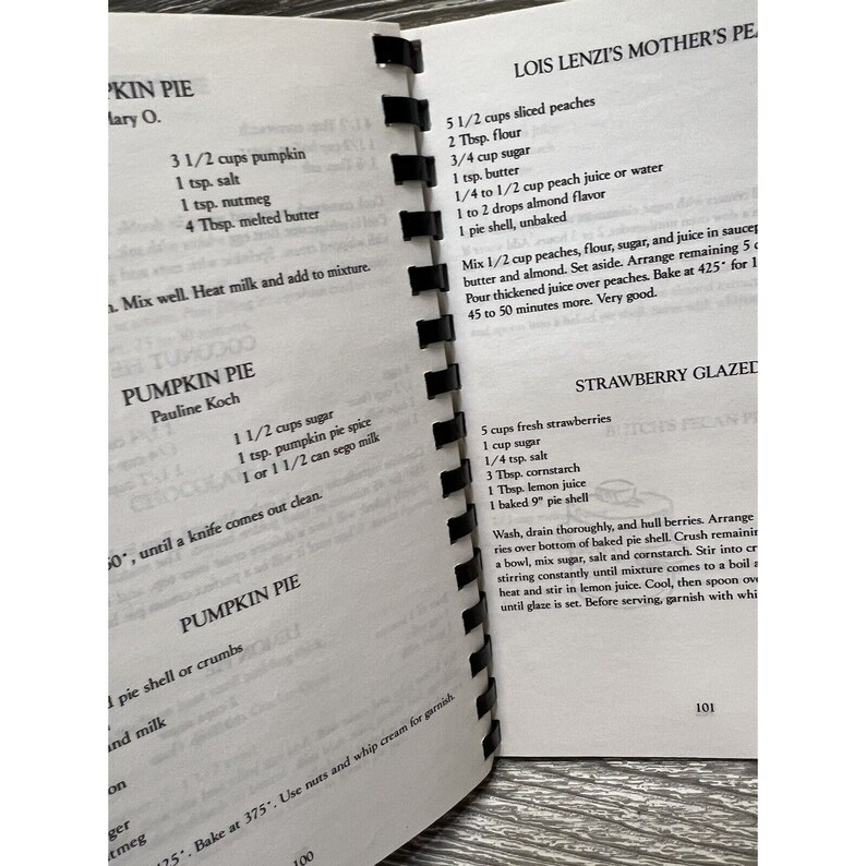 Puede incluir: Un libro de cocina vintage con recetas de pastel de calabaza, pastel de fresa glaseado y pastel de melocot&oacute;n. El libro de cocina tiene una cubierta marr&oacute;n con texto blanco y est&aacute; abierto en una p&aacute;gina con instrucciones para hacer pastel de fresa glaseado.