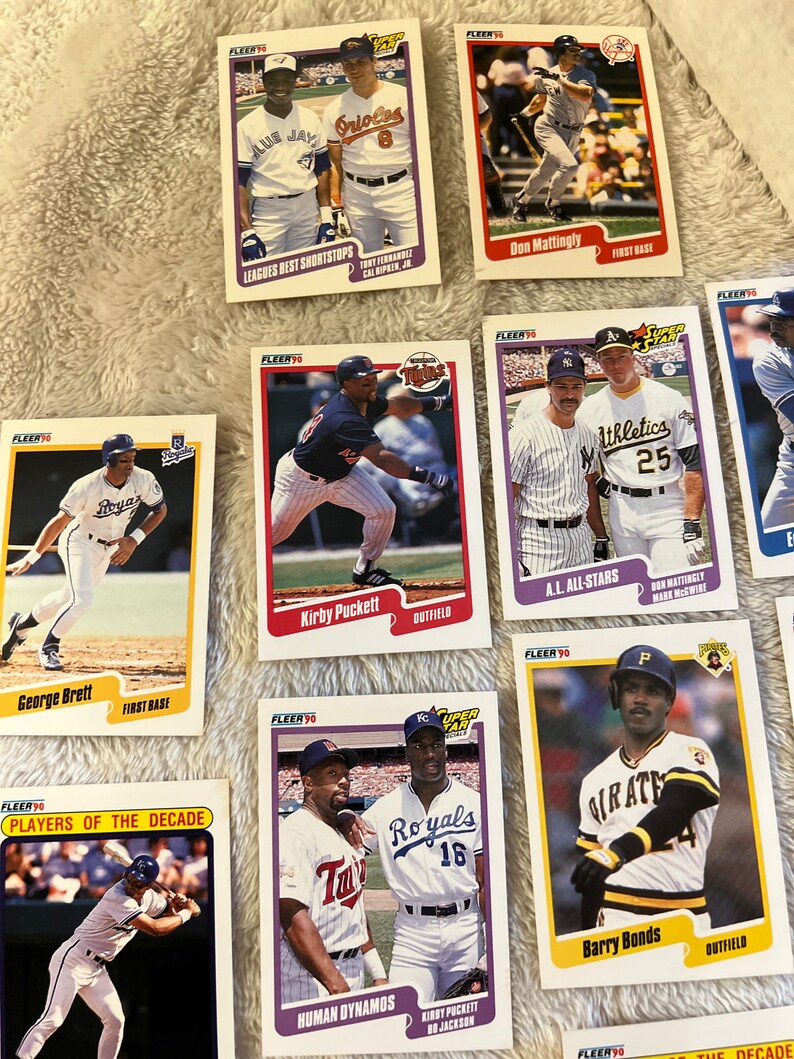 K&ouml;nnte beinhalten: Eine Sammlung von Baseball-Sammelkarten mit verschiedenen Spielern aus den 1990er Jahren. Die Karten stammen aus der Fleer Super Stars-Serie und zeigen Spieler wie George Brett, Kirby Puckett, Don Mattingly und Barry Bonds.