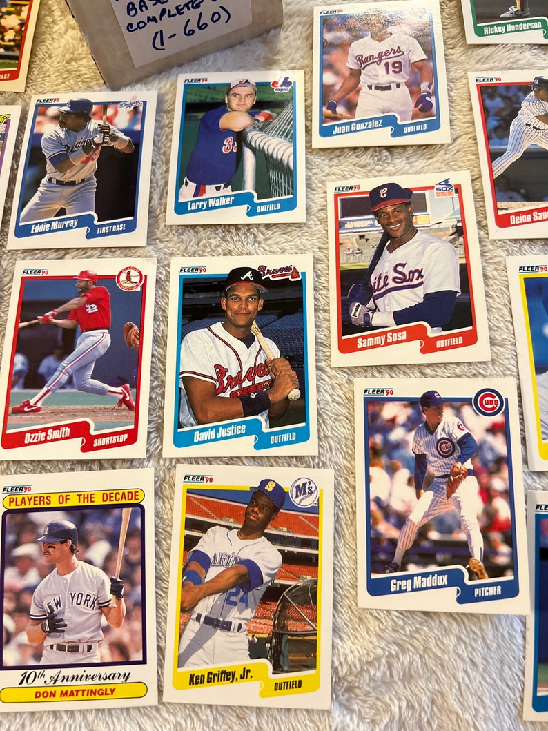 K&ouml;nnte beinhalten: Eine Sammlung von Baseball-Sammelkarten mit verschiedenen Spielern aus verschiedenen Teams. Die Karten stammen aus der Fleer-Serie von 1990 und zeigen Spieler wie Eddie Murray, Larry Walker, Ozzie Smith, David Justice, Sammy Sosa, Greg Maddux, Ken Griffey Jr. und Don Mattingly. Die Karten sind in gutem Zustand und haben einen wei&szlig;en Hintergrund mit blauen und roten Akzenten.