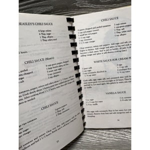 Puede incluir: Un libro de cocina vintage con recetas escritas a mano para salsa de chile, salsa blanca y salsa de vainilla. Las recetas incluyen ingredientes como cebollas, pimientos, tomates, az&uacute;car y especias.