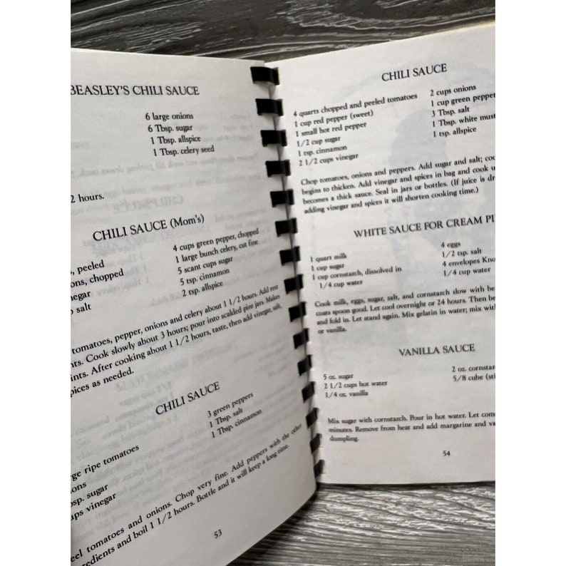 Puede incluir: Un libro de cocina vintage con recetas escritas a mano para salsa de chile, salsa blanca y salsa de vainilla. Las recetas incluyen ingredientes como cebollas, pimientos, tomates, az&uacute;car y especias.