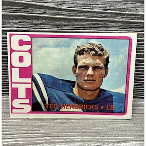 May include: A vintage football trading card featuring a portrait of Ted Hendricks, a linebacker for the Colts. The card has a pink background with the word "COLTS" in white letters.