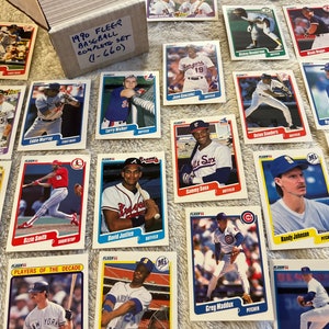 K&ouml;nnte beinhalten: Eine Sammlung von 1990 Fleer Baseballkarten mit verschiedenen Spielern, darunter Sammy Sosa, Greg Maddux und Ryne Sandberg. Die Karten sind in einem Raster auf einer wei&szlig;en Oberfl&auml;che angeordnet. Der Text "1990 FLEER BASEBALL COMPLETE SET (1-660)" ist auf einem blau-wei&szlig;en Kasten in der oberen linken Ecke des Bildes sichtbar.