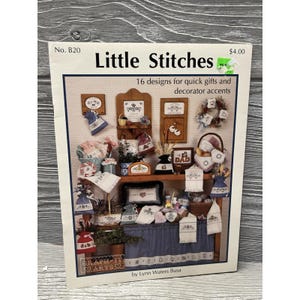 May include: A book cover titled "Little Stitches" with the text "16 designs for quick gifts and decorator accents." The cover displays various cross-stitch designs, including framed pieces, towels, and decorative accents. The price tag shows $4.00.