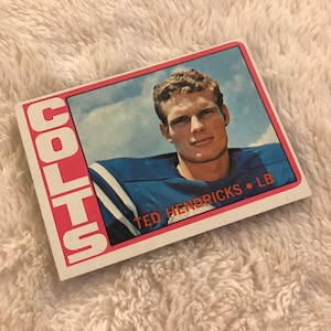 May include: A vintage football trading card featuring a photo of Ted Hendricks, a linebacker for the Colts. The card has a red border with the word "COLTS" printed vertically in white letters.