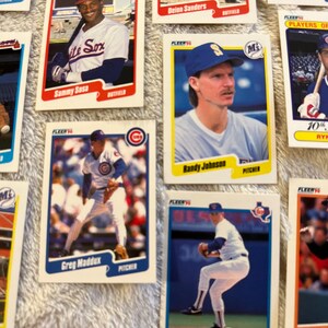 K&ouml;nnte beinhalten: Eine Sammlung von Baseball-Sammelkarten mit Spielern der Chicago Cubs und anderer Teams. Die Karten stammen aus der Fleer-Serie von 1990 und zeigen Spieler wie Sammy Sosa, Greg Maddux und Nolan Ryan.