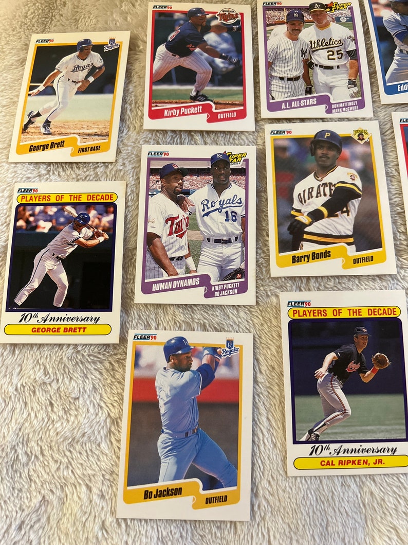 K&ouml;nnte beinhalten: Eine Sammlung von neun Baseball-Sammelkarten mit verschiedenen Spielern aus den 1990er Jahren. Die Karten stammen aus der Fleer 90-Serie und zeigen Spieler wie George Brett, Kirby Puckett, Barry Bonds und Bo Jackson. Die Karten sind in gutem Zustand und haben einen Vintage-Look.