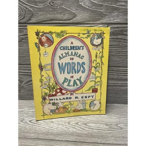 May include: A vintage children's book titled "A Children's Almanac of Words at Play" by Willard R. Espy. The cover is yellow with illustrations of a cat, pig, rabbit, and other whimsical drawings. The title is in a blue and white oval.