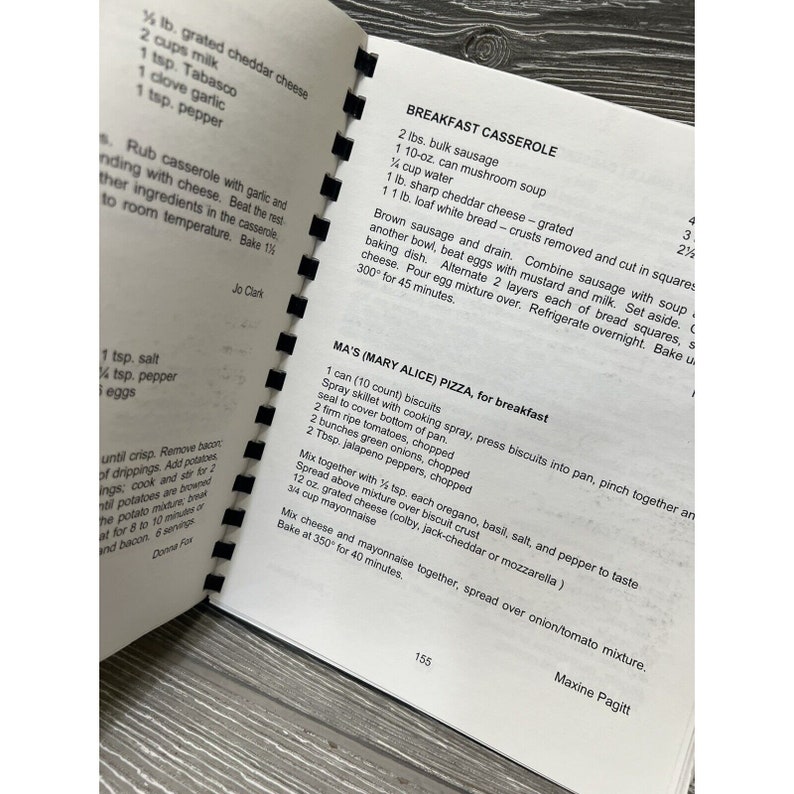 May include: A close-up of a vintage cookbook page with recipes for breakfast casserole and pizza. The recipes include ingredients like sausage, mushroom soup, biscuits, and jalapeno peppers.