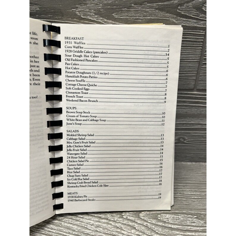 Puede incluir: Un libro de cocina vintage con una portada en blanco y negro. La portada presenta una lista de recetas, que incluyen desayuno, sopas, ensaladas y carnes. Las recetas est&aacute;n numeradas e incluyen platos cl&aacute;sicos como waffles, hot cakes y ensalada de camarones.