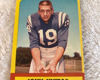 May include: A vintage football trading card featuring John Unitas, quarterback for the Baltimore Colts. The card has a yellow border and a red and white background with the text "John Unitas, Baltimore Colts, Quarterback".