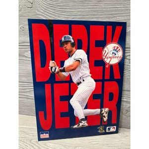 May include: A baseball poster featuring Derek Jeter in a New York Yankees uniform, holding a bat. The background is blue with the name "DEREK JETER" in large red letters. The Yankees logo is visible.