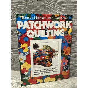 May include: A Better Homes and Gardens book titled "PATCHWORK & QUILTING." The cover features a colorful floral design and a photo of a quilt. The book promises exciting quick-and-easy projects, including quilting, patchwork, and appliqué.