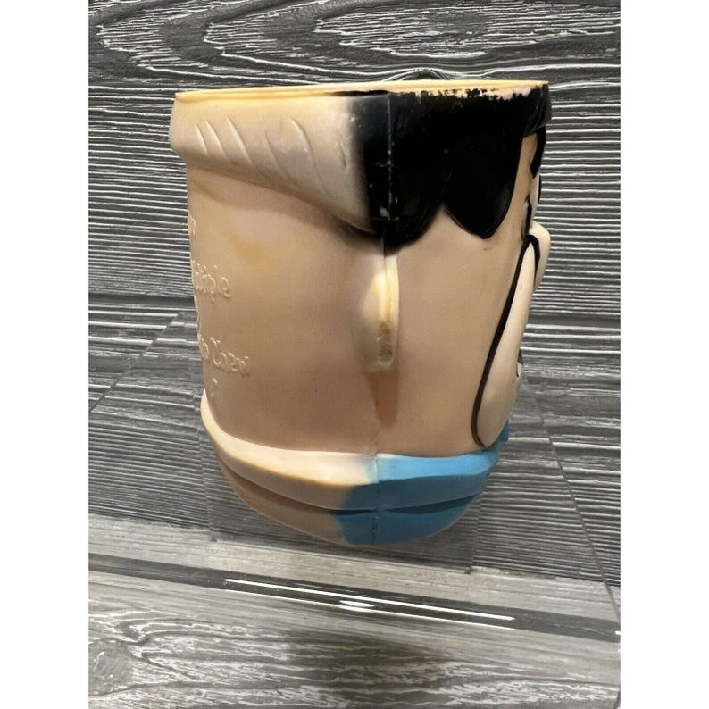 May include: A vintage plastic character head ice bucket with a blue and white design. The character has black hair and a white face.