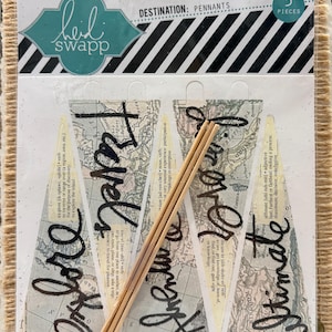 May include: A package of five pennants with a travel theme. The pennants are clear with a map design and black script that reads "Explore", "Adventure", and "Ultimate". The package also includes wooden dowels.