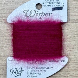 May include: A spool of vibrant magenta Wisper yarn for cross stitch and needlepoint. The label reads "Cross Stitch & Needlepoint for Beards & Animals." The yarn is made in Italy and is 20 yards long.