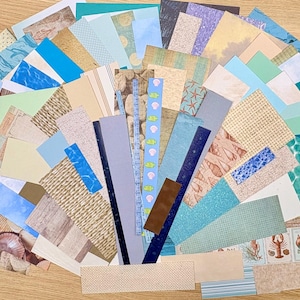 May include: A collection of assorted paper scraps in various shades of blue, green, beige, and brown. The papers feature patterns like seashells, water, and textured designs, ideal for crafting or scrapbooking projects.