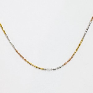 May include: A delicate necklace featuring a tri-color design. The necklace alternates between gold, silver, and rose gold rectangular beads. The chain is displayed against a white background, highlighting the jewelry's elegant simplicity.