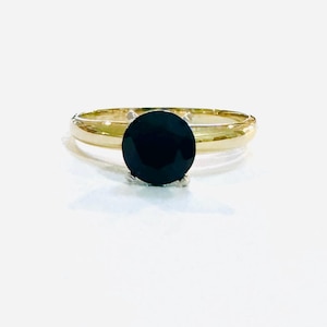May include: A gold ring with a black gemstone in a prong setting.