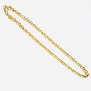 May include: A gold-colored chain necklace with a lobster clasp. The chain is made of small, rectangular links. The necklace is displayed on a white background. Jewelry.