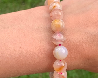 May include: A bracelet made of light pink and brown agate beads with a pink elastic cord.