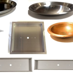 May include: A set of five stainless steel fire pit inserts in various sizes and shapes. The inserts are all made of polished stainless steel and have a smooth, reflective surface. The inserts are designed to be used in a fire pit to create a more even and efficient fire.