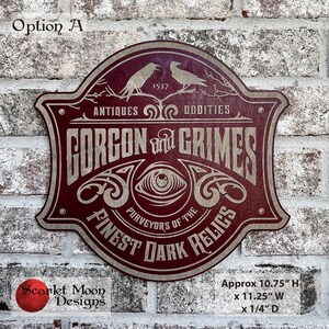 May include: A wooden sign with a burgundy and tan color scheme. The sign reads "GORCON and GRIMES" with the text "ANTIQUES ODDITIES" above and "PURVEYORS OF THE FINEST DARK RELICS" below. The sign is approximately 10.75 inches high, 11.25 inches wide, and 0.25 inches deep.