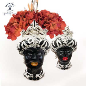 Könnte beinhalten: Zwei schwarze und weiße Keramikvasen in Kopfform mit aufwendigen Designs. Die Vasen zeigen schwarze Gesichter mit weißen Augen und roten Lippen. Die Vasen sind mit schwarzen und weißen Streifen und weißen Spiralen verziert.