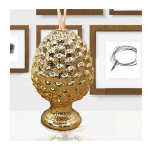 以下が含まれることがあります： 丸い土台と木の棒が付いた、松ぼっくり型の金色のセラミックディフューザー