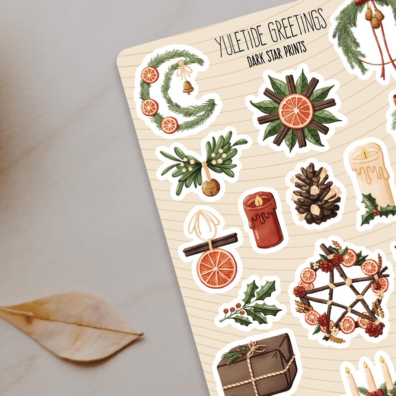 Pu&ograve; includere: Un foglio di adesivi con varie illustrazioni di festivit&agrave; invernali. Gli adesivi sono bianchi con un contorno nero e presentano immagini di ghirlande, candele, pigne e altri elementi festivi. Il testo "YULETIDE GREETINGS DARK STAR PRINTS" &egrave; in cima al foglio.
