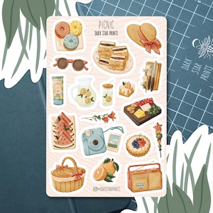 May include: A sticker sheet featuring picnic-themed illustrations. Includes donuts, sandwiches, sunglasses, sunscreen, lemonade, watermelon slices, a camera, a picnic basket, oranges, a radio, and a hat. The text "PICNIC" and "DARK STAR PRINTS" are visible.