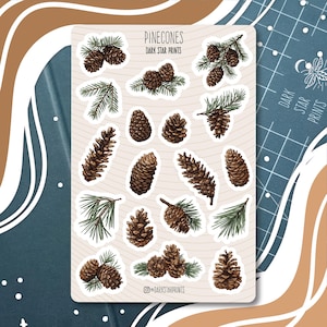 May include: A sticker sheet with illustrations of pinecones and pine branches in brown and green. The text "PINECONES" and "DARK STAR PRINTS" are at the top. The Instagram handle "@DARKSTARPRINTS" is displayed at the bottom of the sheet.